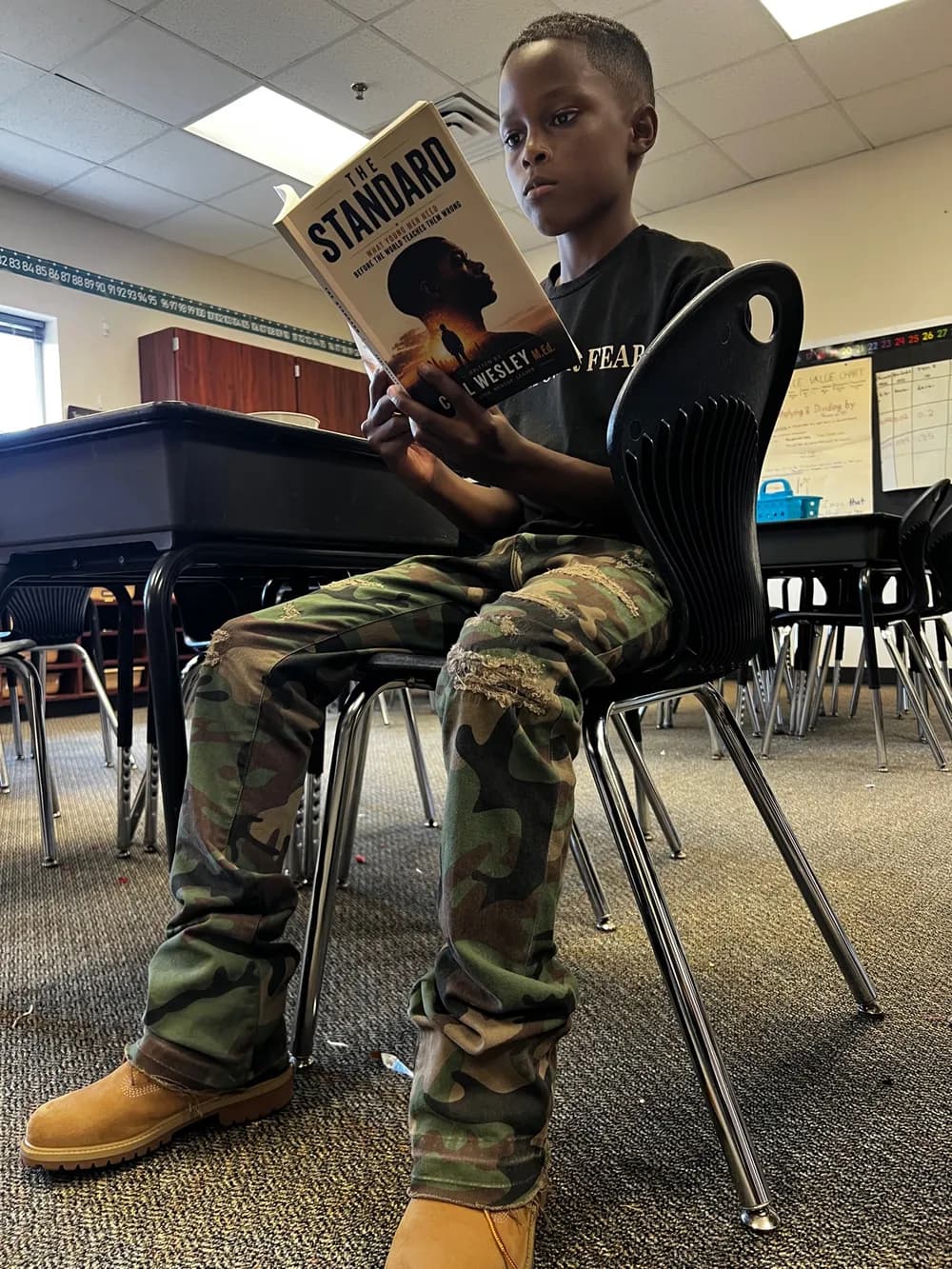 A young reader in class holding his copy of The Standard